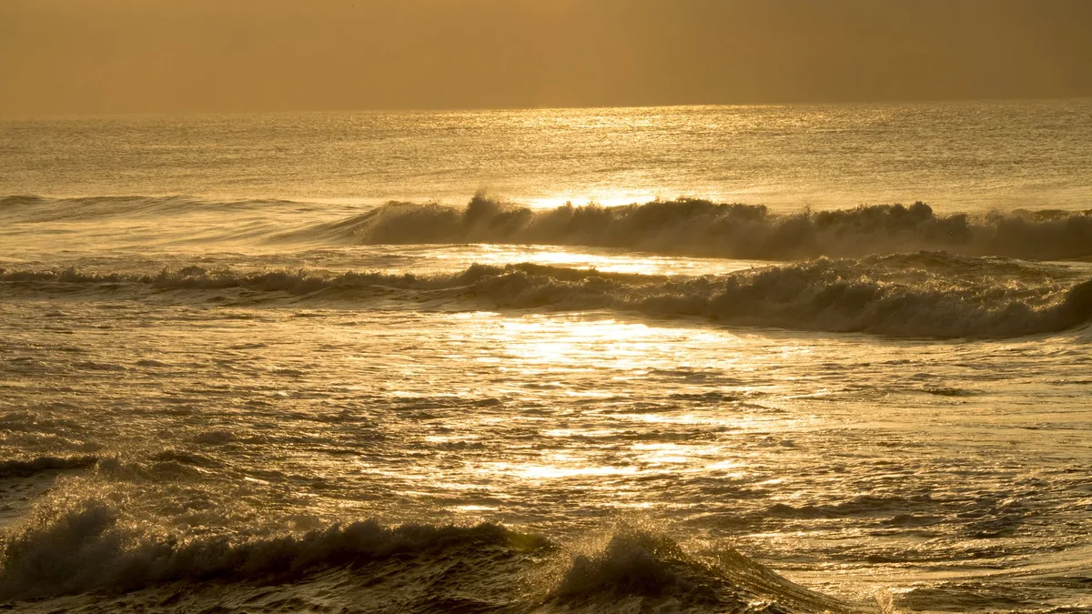 Captivating sunrise over the ocean with golden hues reflecting on waves, creating a serene seascape.